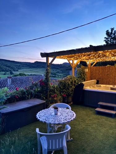 a patio with a table and chairs and a tub at L'écrin vert in Villelongue-dʼAude