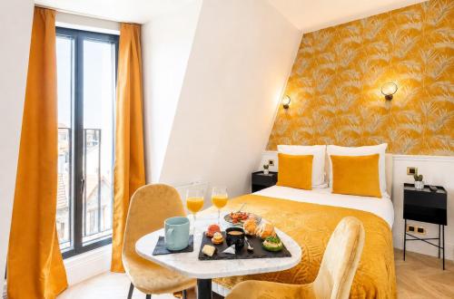 a hotel room with a bed with a tray of food on a table at Hôtel Mijo's in Fontenay-sous-Bois