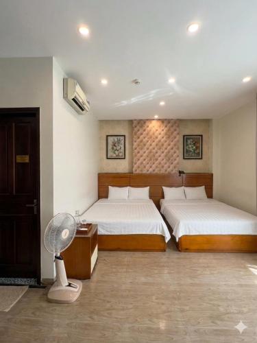 a bedroom with two beds and a fan in it at An Phú Nguyễn Hoàng Hotel in Hanoi