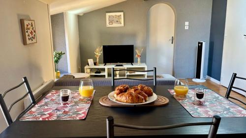 a table with a plate of croissants and orange juice at Zen Appartement Centre-ville historique in Niort