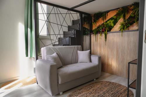 a living room with a white chair and a painting at Malpensa Elegant Loft in Gallarate