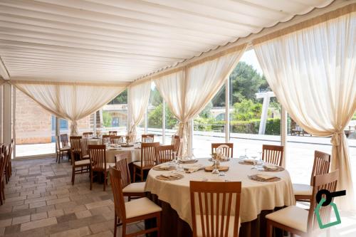 a dining room with tables and chairs and windows at Hotiday Gallipoli Sannicola in Gallipoli