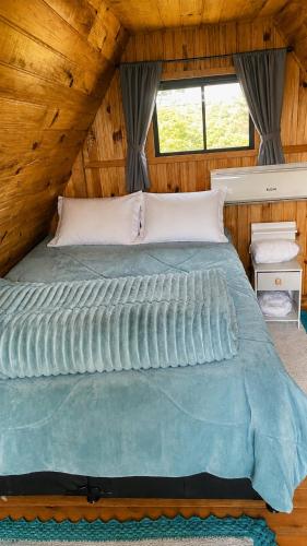 a large bed in a room with a wooden ceiling at Chalés Recanto da Serra in Bocaina do Sul