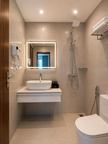 a bathroom with a sink and a toilet and a mirror at Hestia Hotel Móng Cái in Móng Cái
