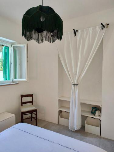 a bedroom with a bed with a curtain and a chair at Bianco e Rosmarino in Selva di Fasano