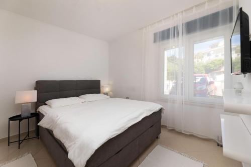 a white bedroom with a large bed and a window at Studio apartman Lea in Baška