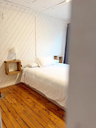a bedroom with a white bed and a wooden floor at Ola in Puchuncaví