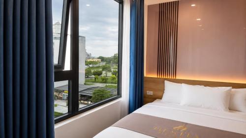 a bedroom with a bed and a large window at Hestia Hotel Móng Cái in Móng Cái