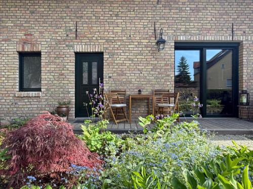 Eine Terrasse mit Stühlen und Blumen vor einem Backsteingebäude in der Unterkunft Am Scheunengarten in Klausdorf Brandenburg