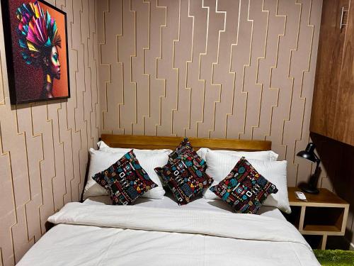 a bedroom with a bed with four pillows on it at Cozy haven in Kampala