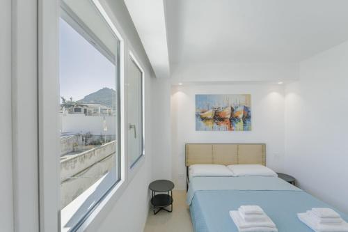 two beds in a white room with a window at Almarè Affittacamere in Favignana