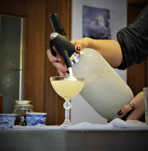 a woman pouring a drink into a wine glass at Hotel Rotwand in Laives