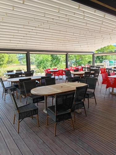 a dining area with tables and chairs in a building at Camping Mas Sud Ardèche in Saint-Just