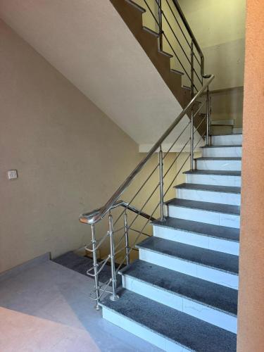a staircase with a metal handrail and a stool at Hamsun DHA in Karachi