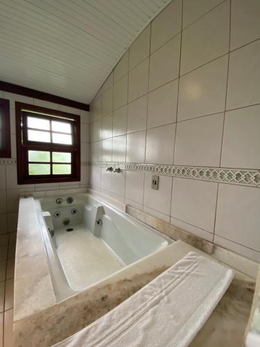 a large bath tub in a bathroom with a window at Pousada Halliny do Rosa in Praia do Rosa