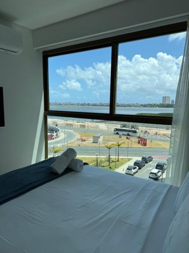 a bed in a room with a large window at Flat Parque do Cais in Recife By Flatbpaiva in Recife