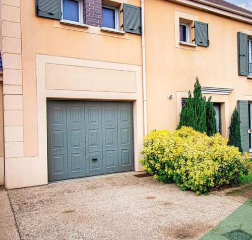 a house with a garage door and a bush at Villa Near Versailles in Feucherolles