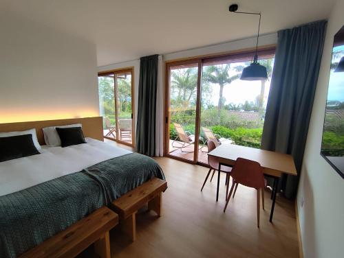 a bedroom with a bed and a table and a window at Quinta dos Curubas in Vila Franca do Campo