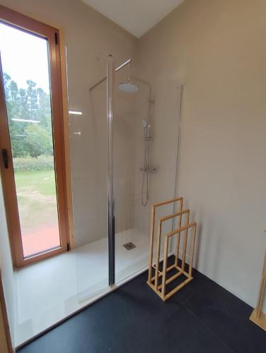 a bathroom with a shower and a chair next to a window at Quinta dos Curubas in Vila Franca do Campo