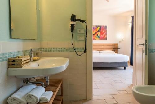 a bathroom with a sink and a shower and a bed at Hotel La Posta di Torrenova in Orbetello