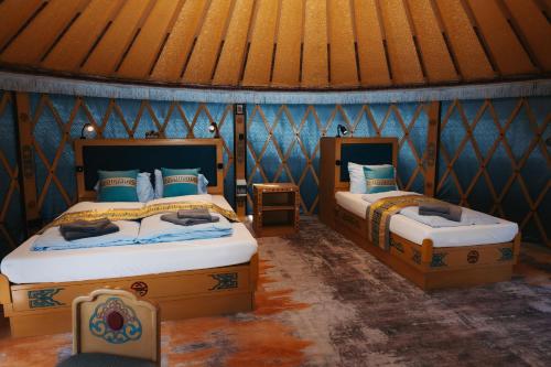 two beds in a room with blue walls at Yurt Mongolia - Camp La Belle Vie in Berdorf