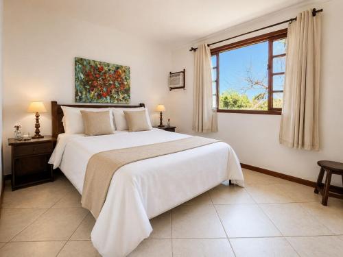 a white bedroom with a large bed and a window at EstrelaMar Boutique in Búzios