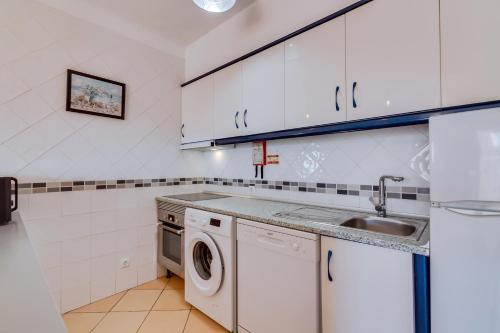 a kitchen with a sink and a washing machine at Vale do Farol Cozy Retreat in Quarteira