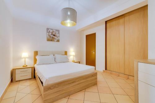 a bedroom with a bed and a cabinet and lights at Vale do Farol Cozy Retreat in Quarteira