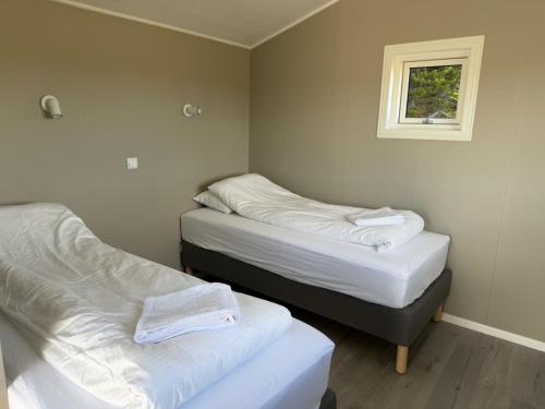 two beds in a small room with a window at Lífsbót - riverside cottage in Egilsstaðir