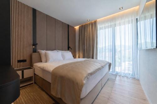 a bedroom with a large bed and a large window at Home apartments in Mostar