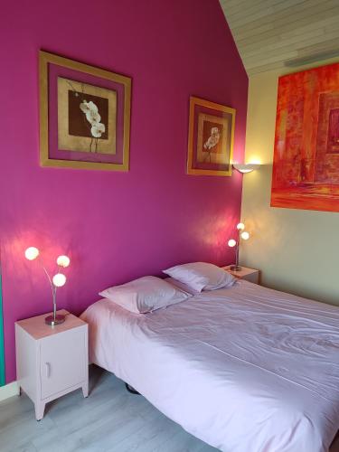 a bedroom with a pink wall with a bed and two lamps at Chez Herveline Le Fer - Chambres et table d'hôtes in Plouigneau