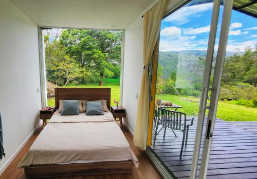 a bedroom with a bed and a balcony with a view at Kolibri Containers Boyacá in Guayatá