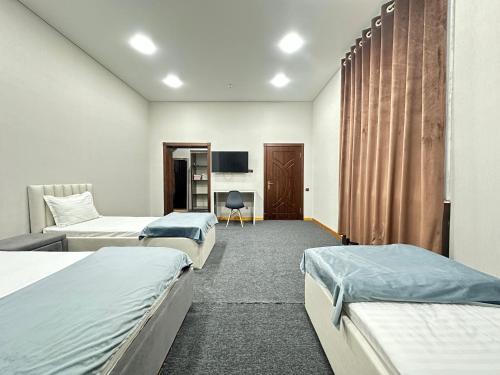 a hotel room with three beds and a tv at Center Hotel Darhan in Tashkent