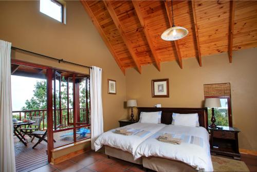 a bedroom with a bed and a balcony at The Loerie's View in Wilderness