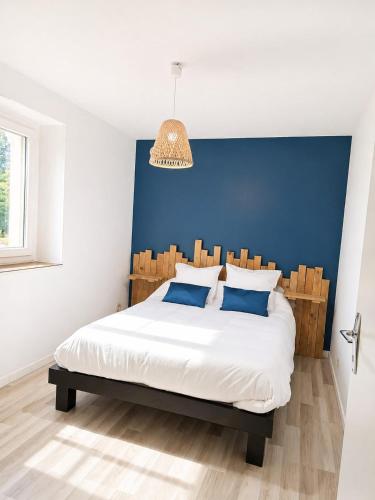 a bedroom with a large bed with a blue wall at L'échappée Verte in Saint-Jean-la-Bussière