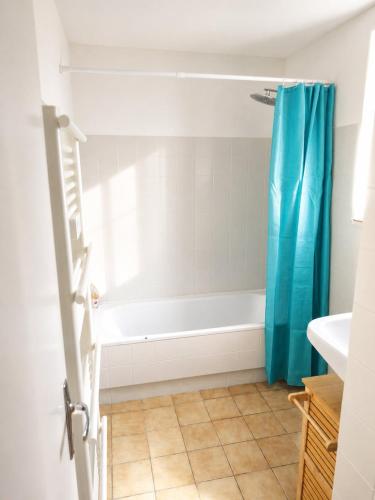 a bathroom with a blue shower curtain and a tub at L'échappée Verte in Saint-Jean-la-Bussière