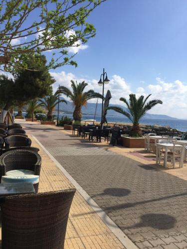 a walkway with tables and chairs on the beach at Calma4 in Agioi Theodoroi