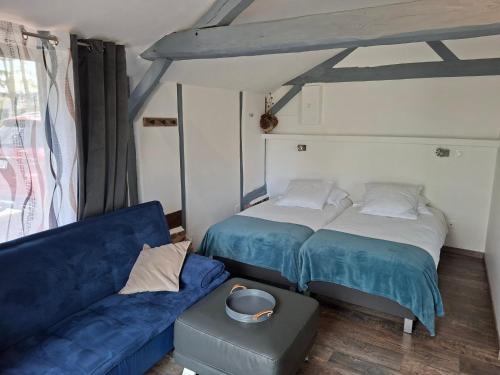 a bedroom with two beds and a blue couch at Gîte, Le Séchoir à Lin demeure de charme in Veauville-les-Baons