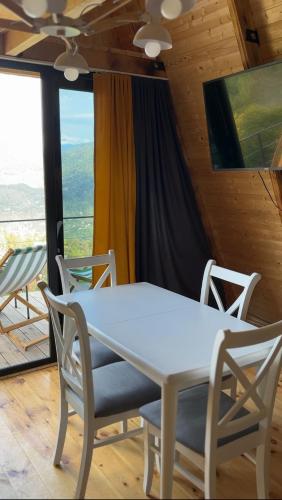 a table and chairs in a room with a view at HillSide Cottage-ჰილსაიდ კოტეჯი in K'eda
