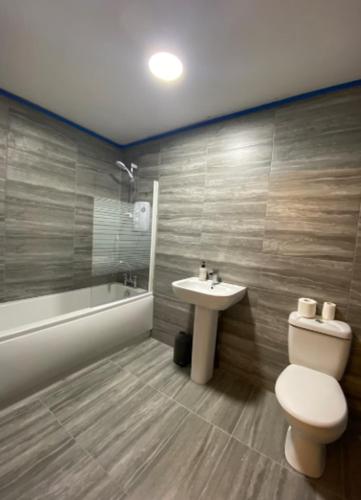 a bathroom with a toilet and a sink and a tub at Roomello luxury City Studios in Peterborough