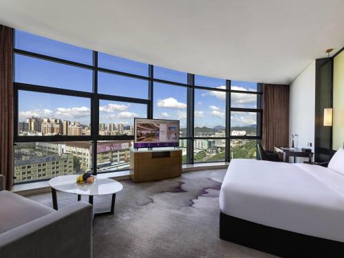 a hotel room with a bed and a flat screen tv at Mercure Shenzhen Longgang in Shenzhen
