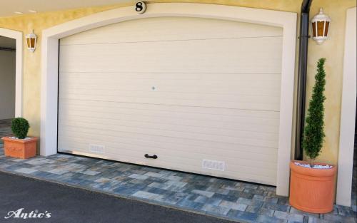 a white garage door with two potted plants at Motel pizzeria Antic's in Laktaši