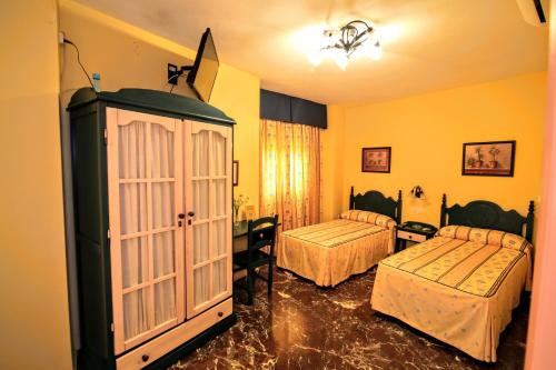 ein Hotelzimmer mit 2 Betten und einem Schrank in der Unterkunft Pension Rural La Fonda in Dúrcal