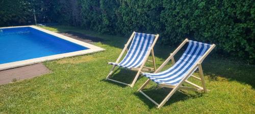 zwei Stühle stehen im Gras neben einem Swimmingpool in der Unterkunft Villa Fabiola in Fogás de Tordera