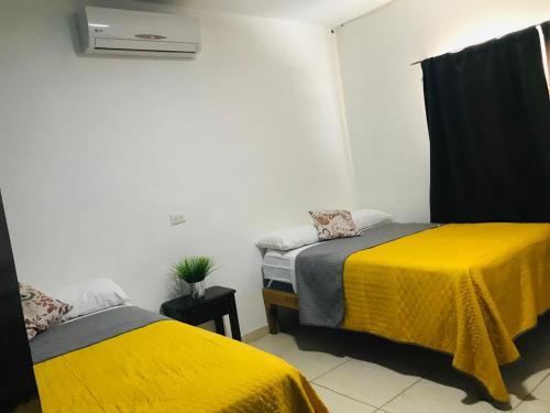 two beds in a room with yellow sheets at Casa Bell in Ciudad Valles