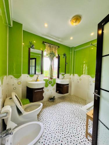 a green bathroom with two sinks and two toilets at Ami Residence Bucharest Airport,Therme&FREE PARKING Otopeni in Otopeni