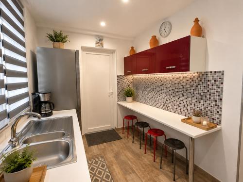 a kitchen with a sink and some red stools at Au lit de Vin in Saint-Sulpice-de-Faleyrens