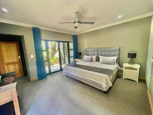 a bedroom with a large bed with blue curtains at Greens & Dreams in Parys