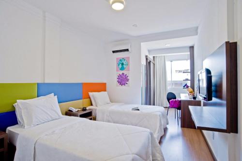 a hotel room with two beds and a television at GoldMen Business Joinville in Joinville