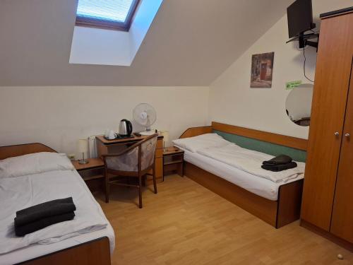 a room with two beds and a desk with a computer at Penzion Borlitz in Pohořelice